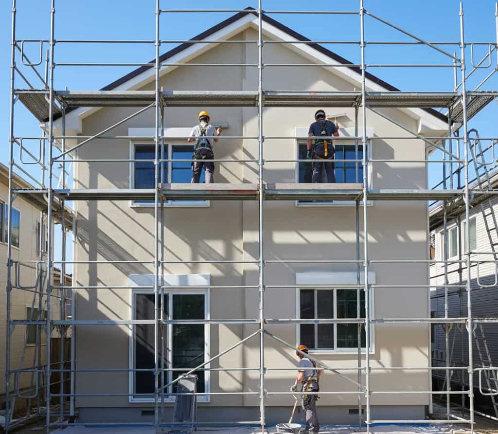 Rénovation de façade de maison avec échafaudages et ouvriers illustrant un projet de refaire une façade et les démarches d’urbanisme à connaître